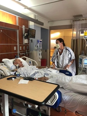 Brooke standing next to her father Donald while he is in a hospital bed